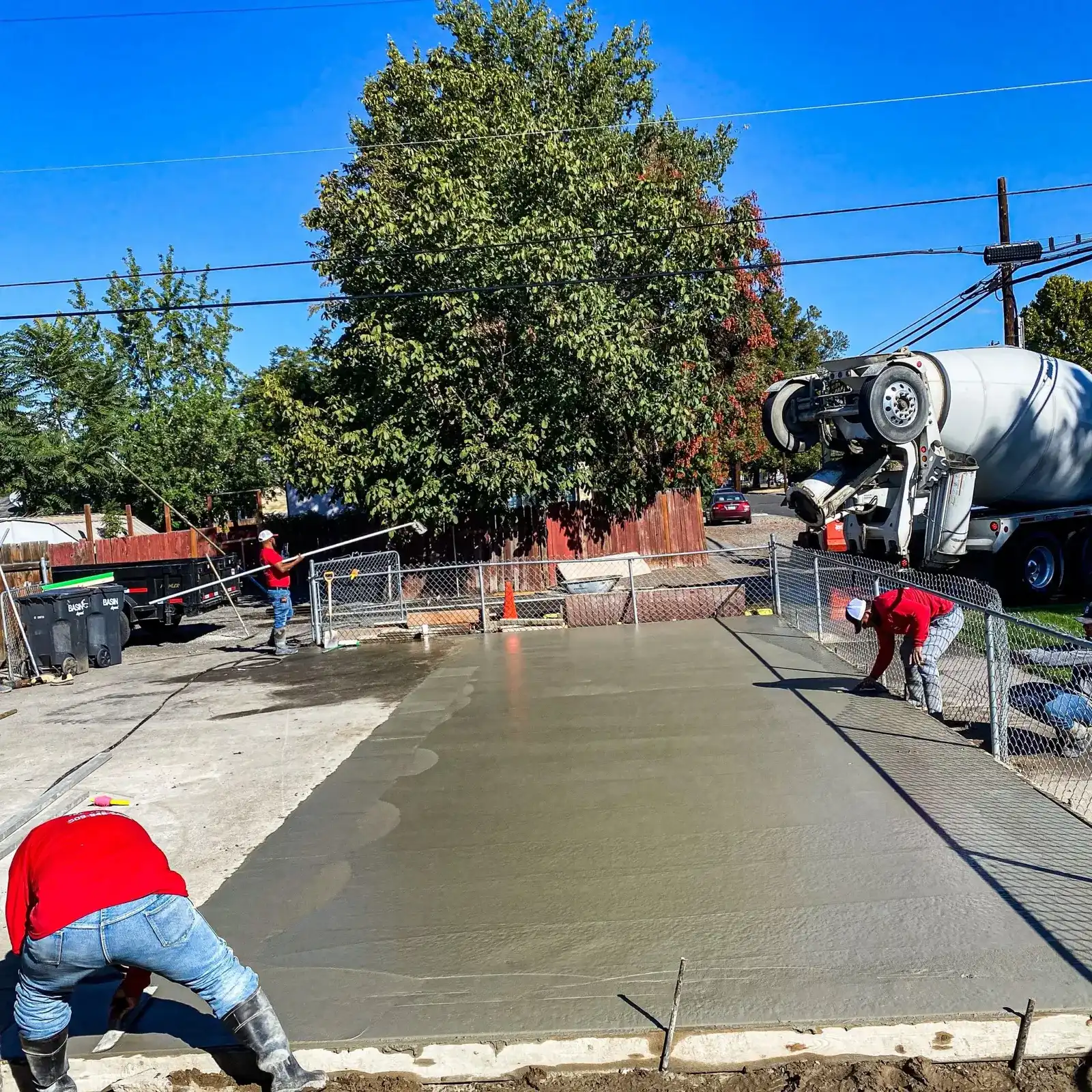H&N Concrete crew screeding a large freshly poured residential slab, mixer truck behind
