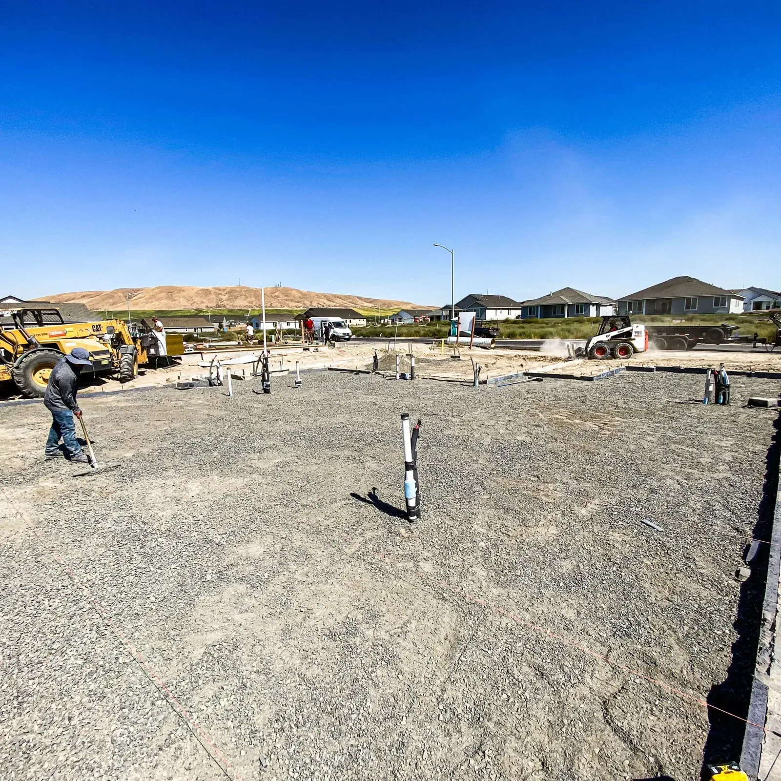 Graded foundation pad with plumbing stub-outs ready for the pour