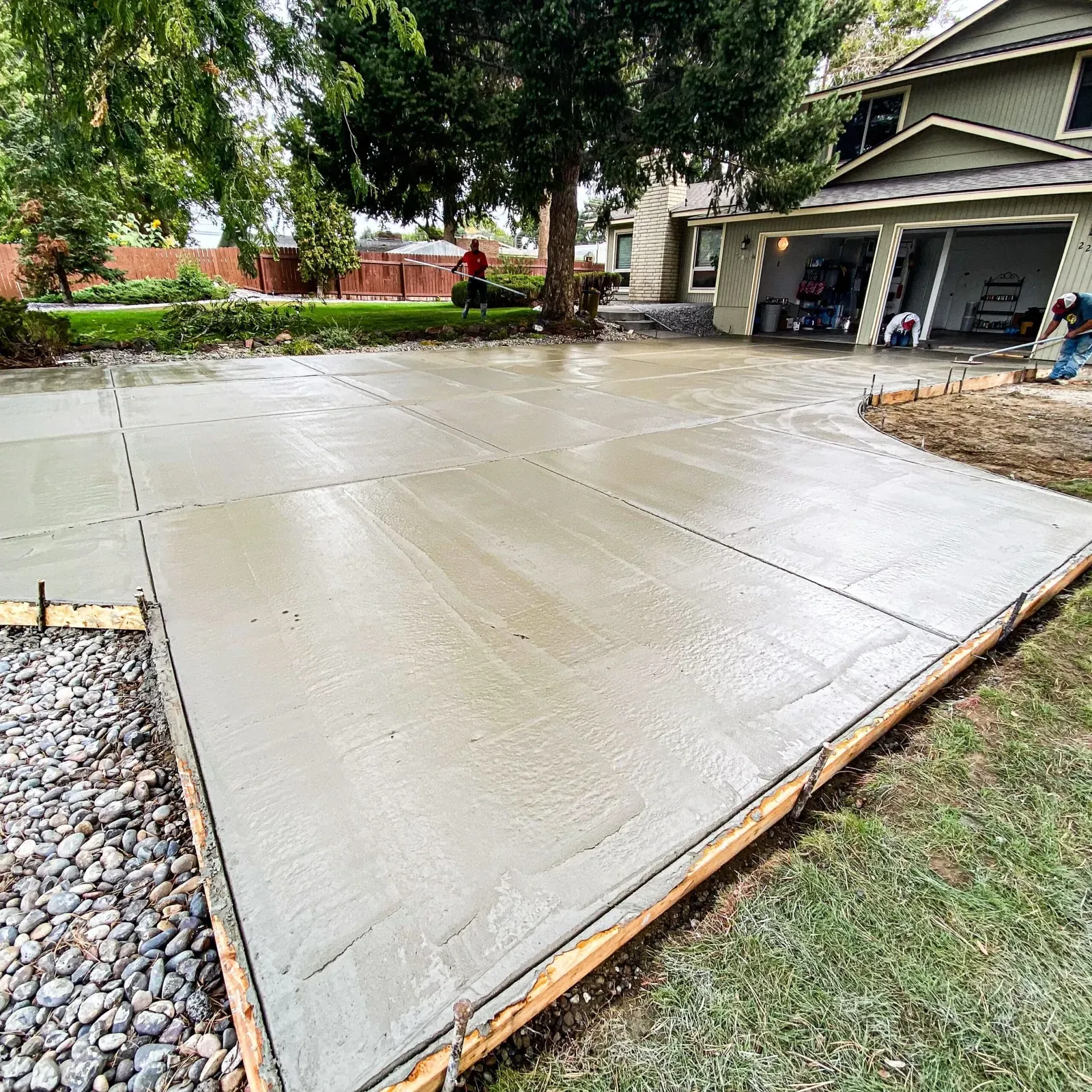Wide freshly finished concrete driveway beside a green lawn