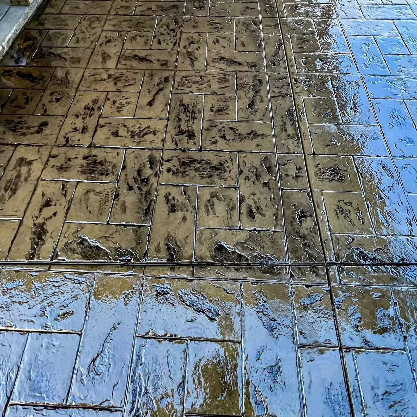 Freshly stamped and sealed concrete glistening in a stone tile pattern