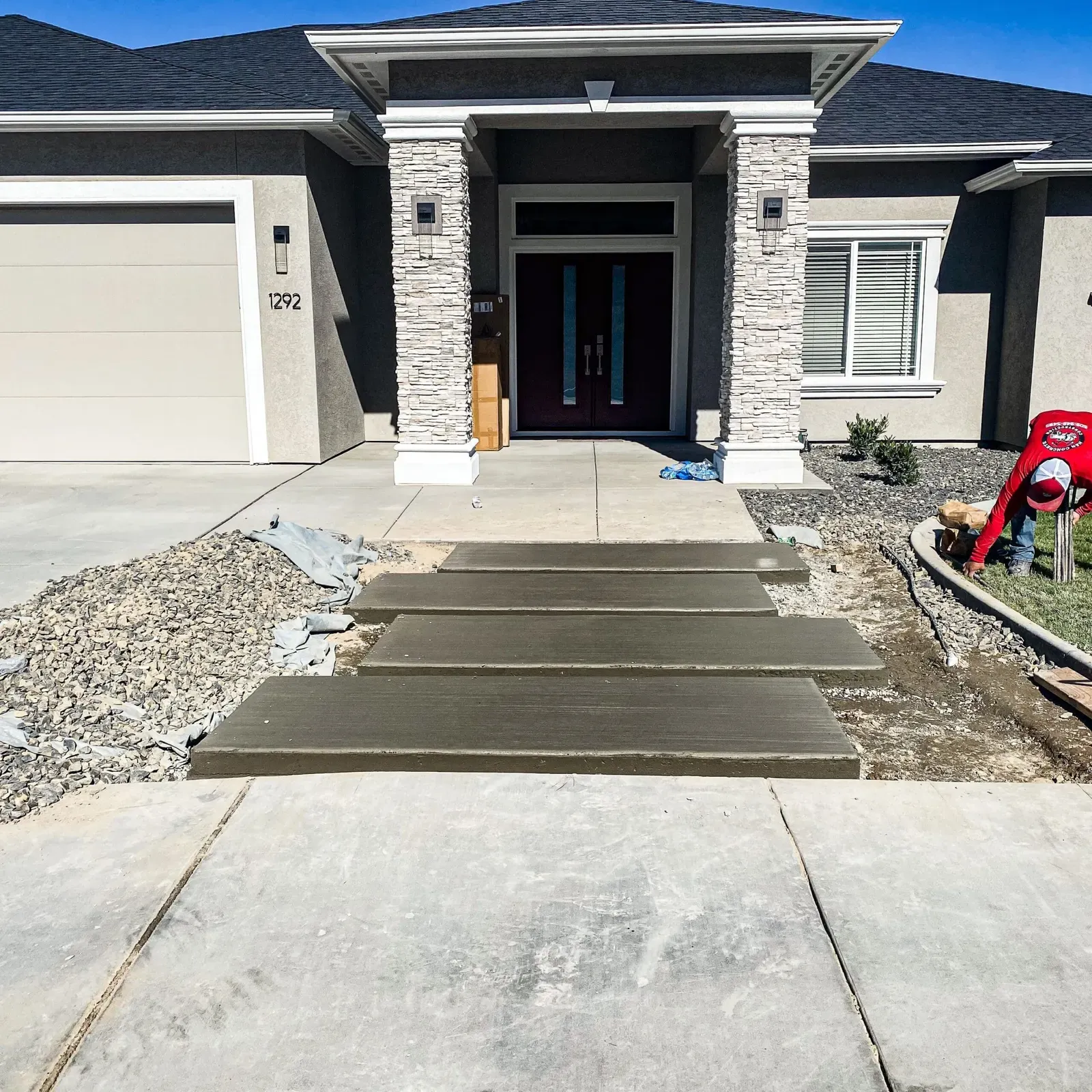 New concrete entry steps and walkway at a modern stone-accent home