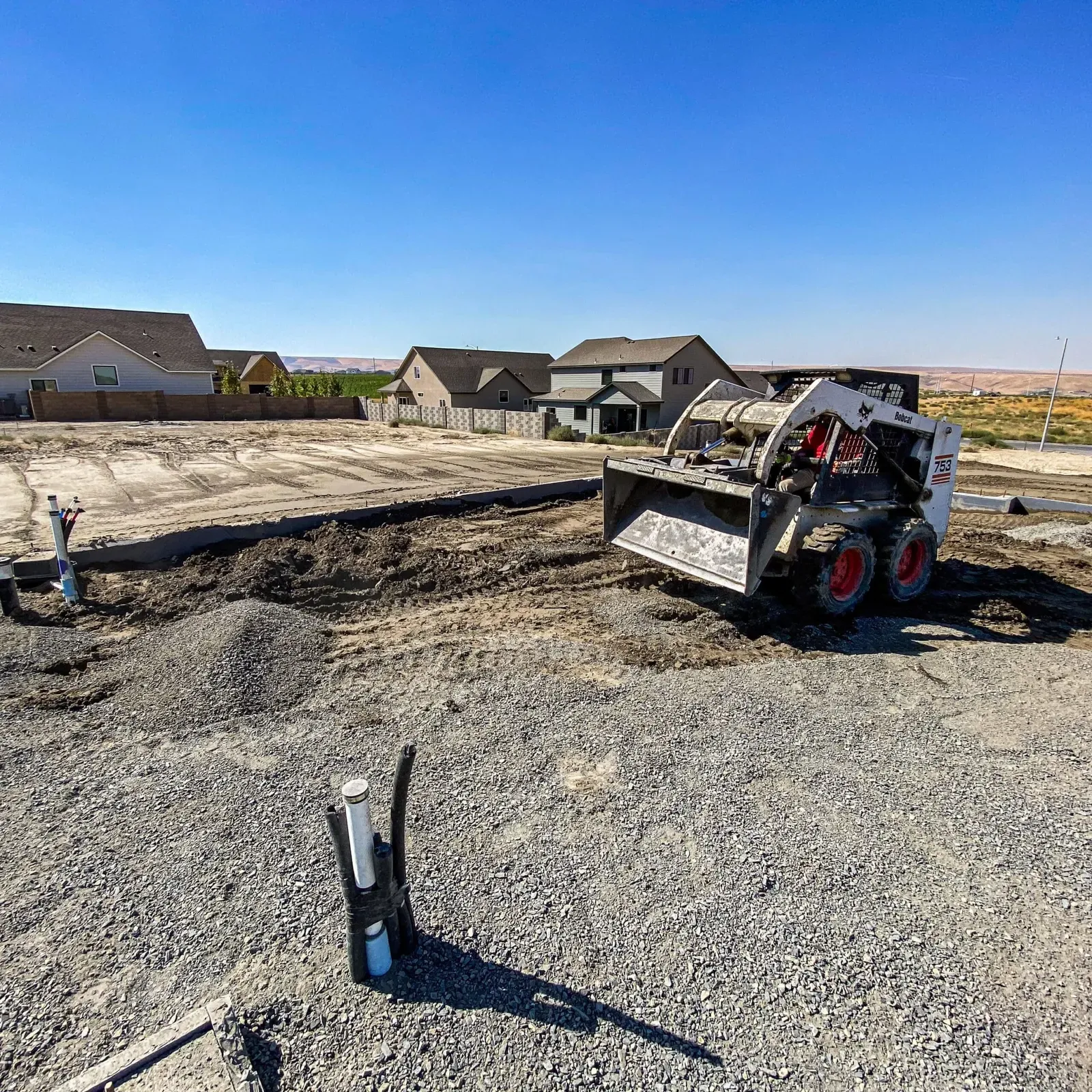 Skid steer grading a building pad before the foundation pour