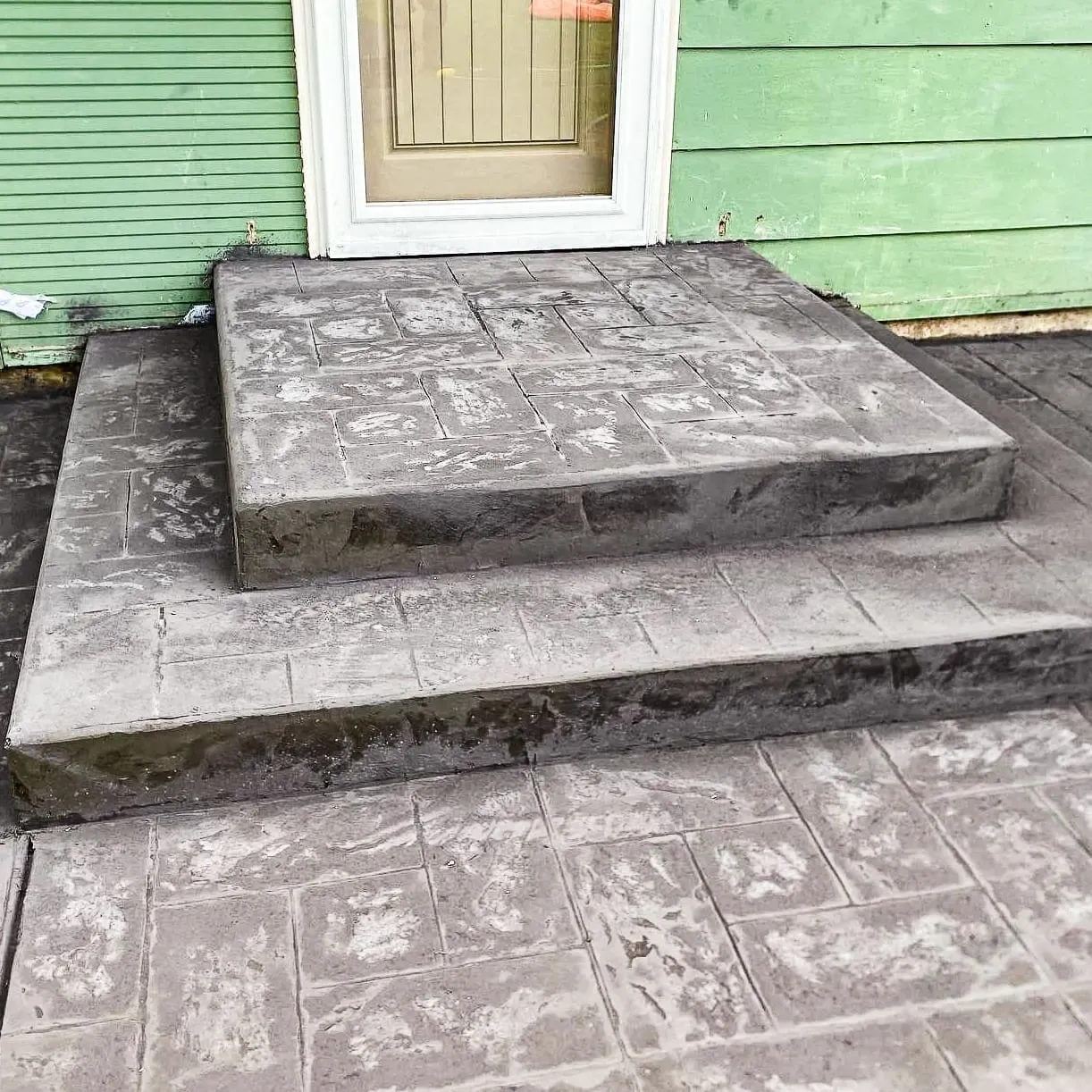 Stamped concrete steps in a weathered stone texture at a front door