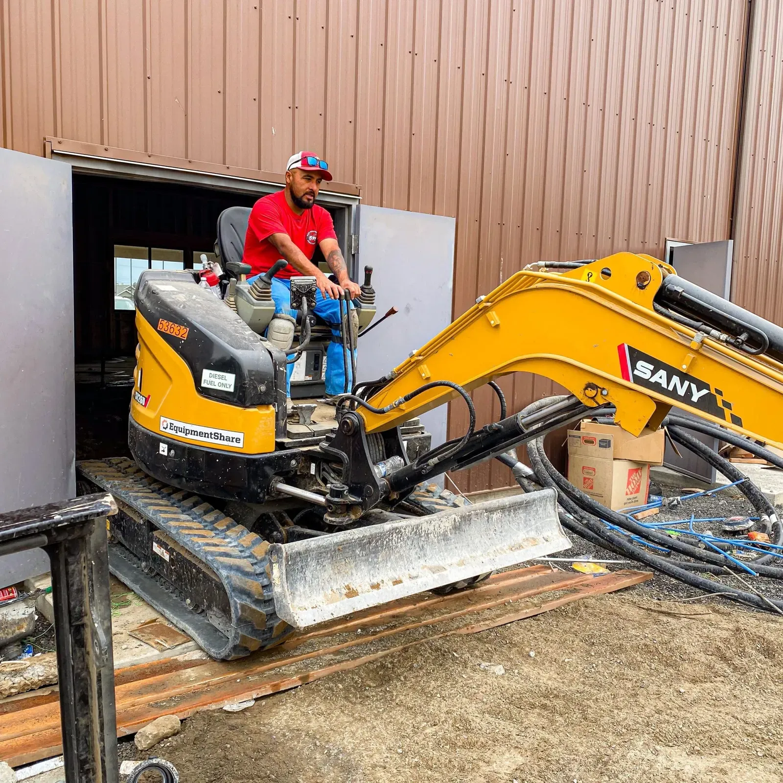 Crew member operating a mini excavator on a demolition job