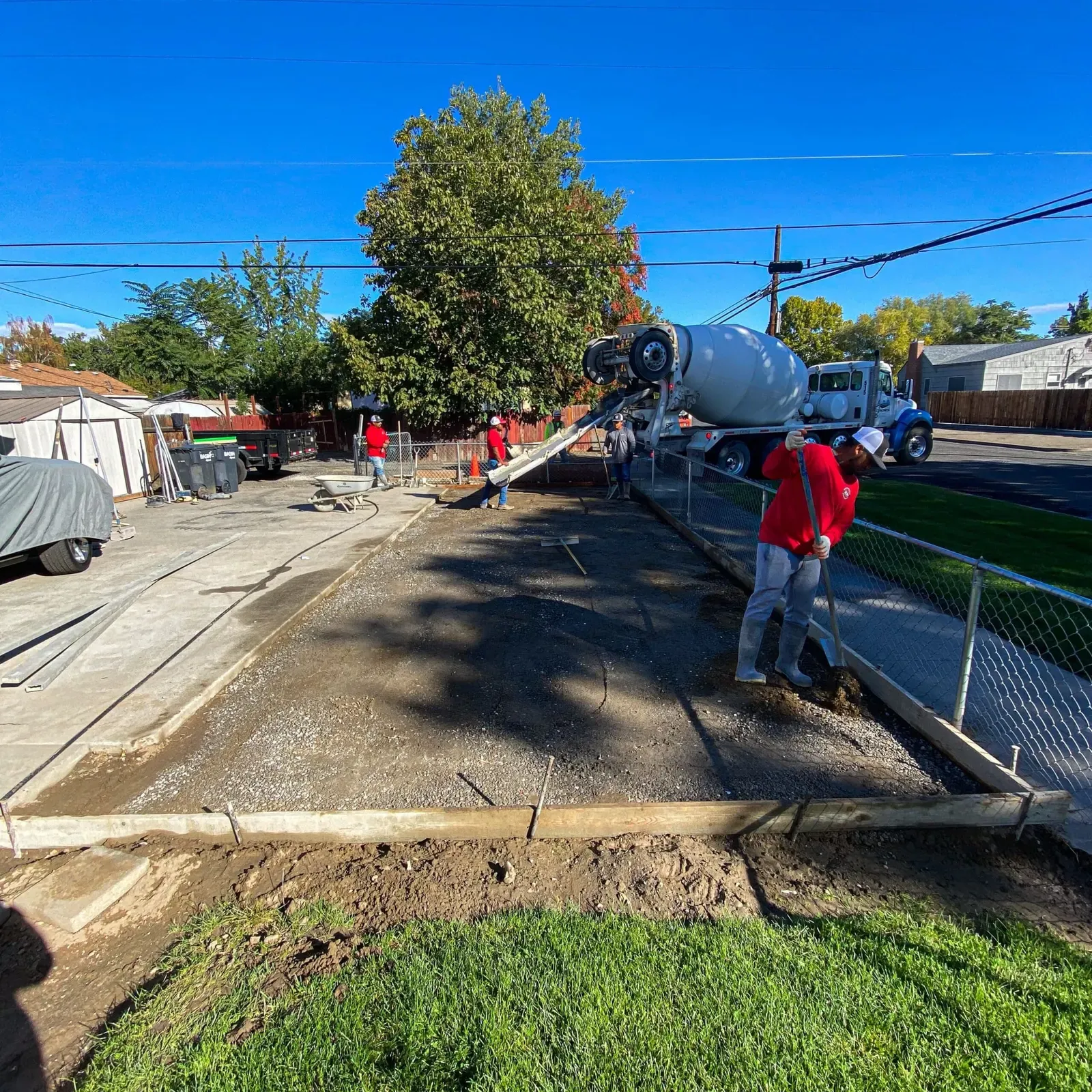 Mixer truck chute pouring a new sidewalk while the crew screeds