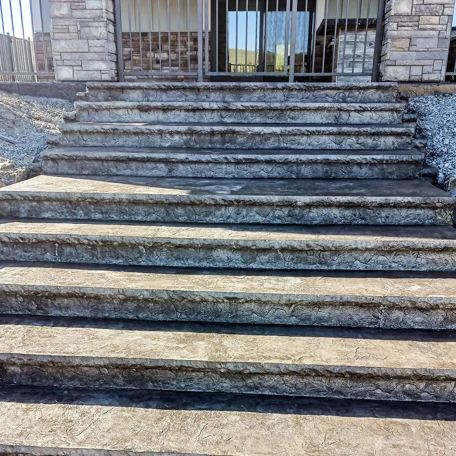 Wide stamped concrete steps in a natural stone look at a stone-front home