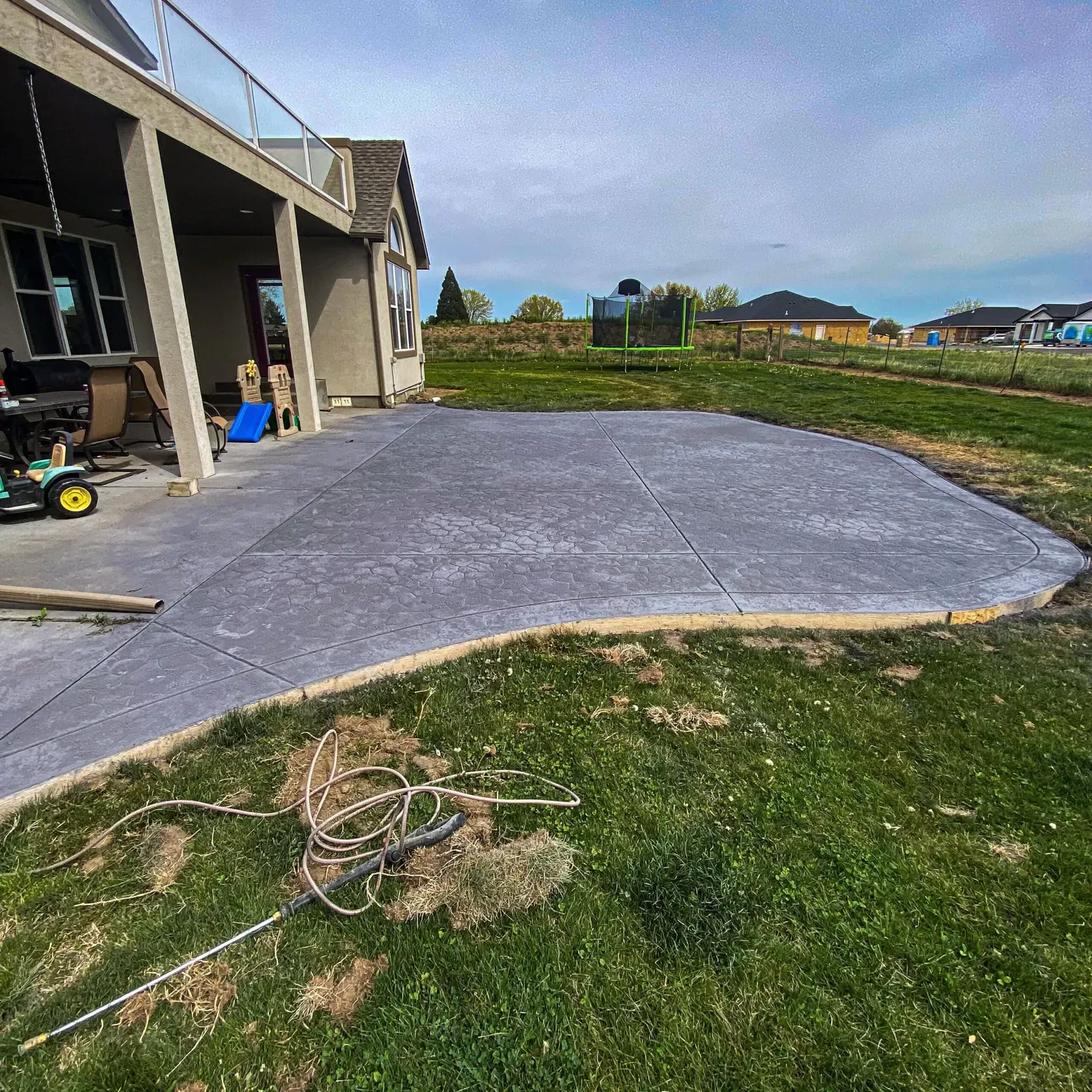 Freshly poured curved patio slab behind a country home