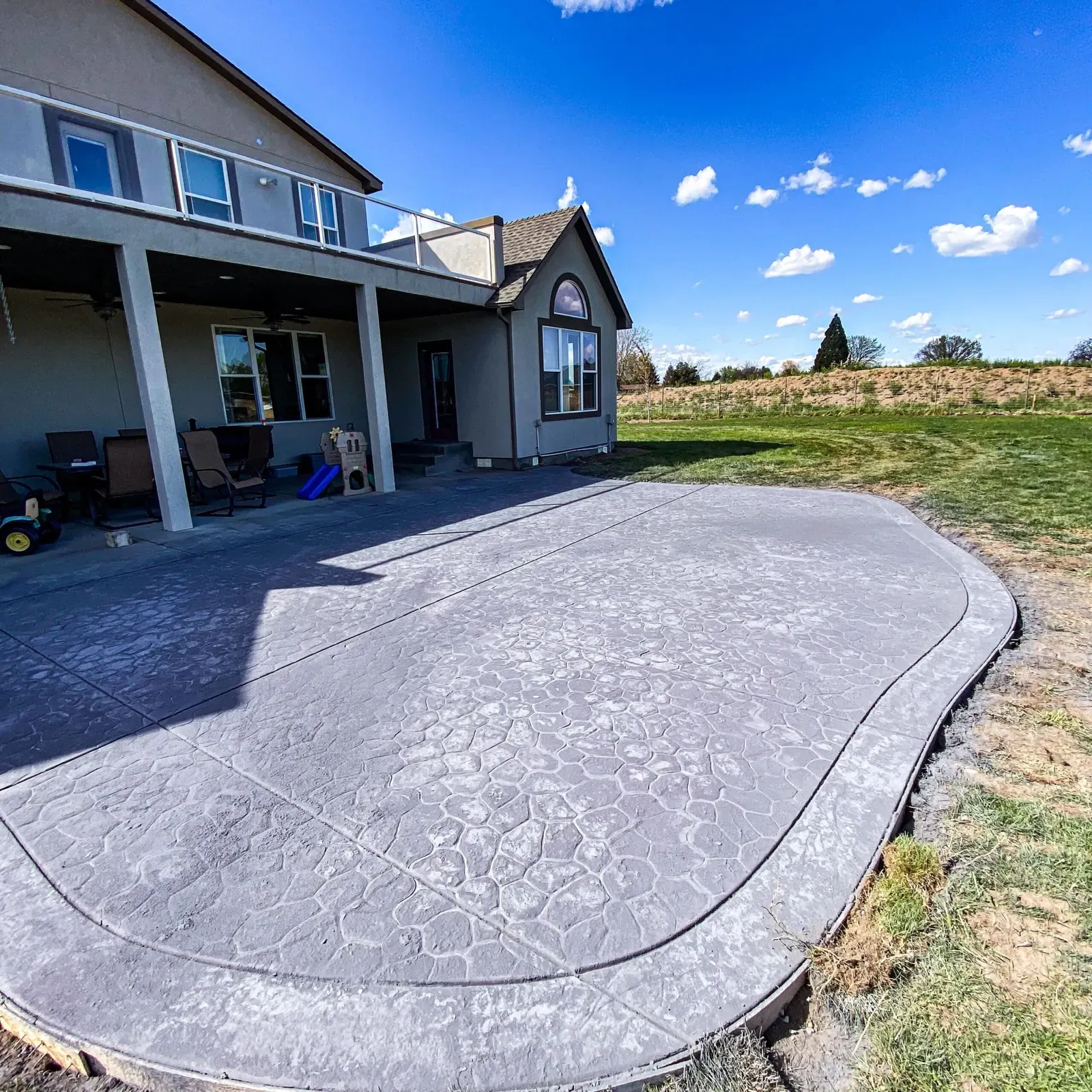 Curved stamped patio with a seamless stone texture at a rural home